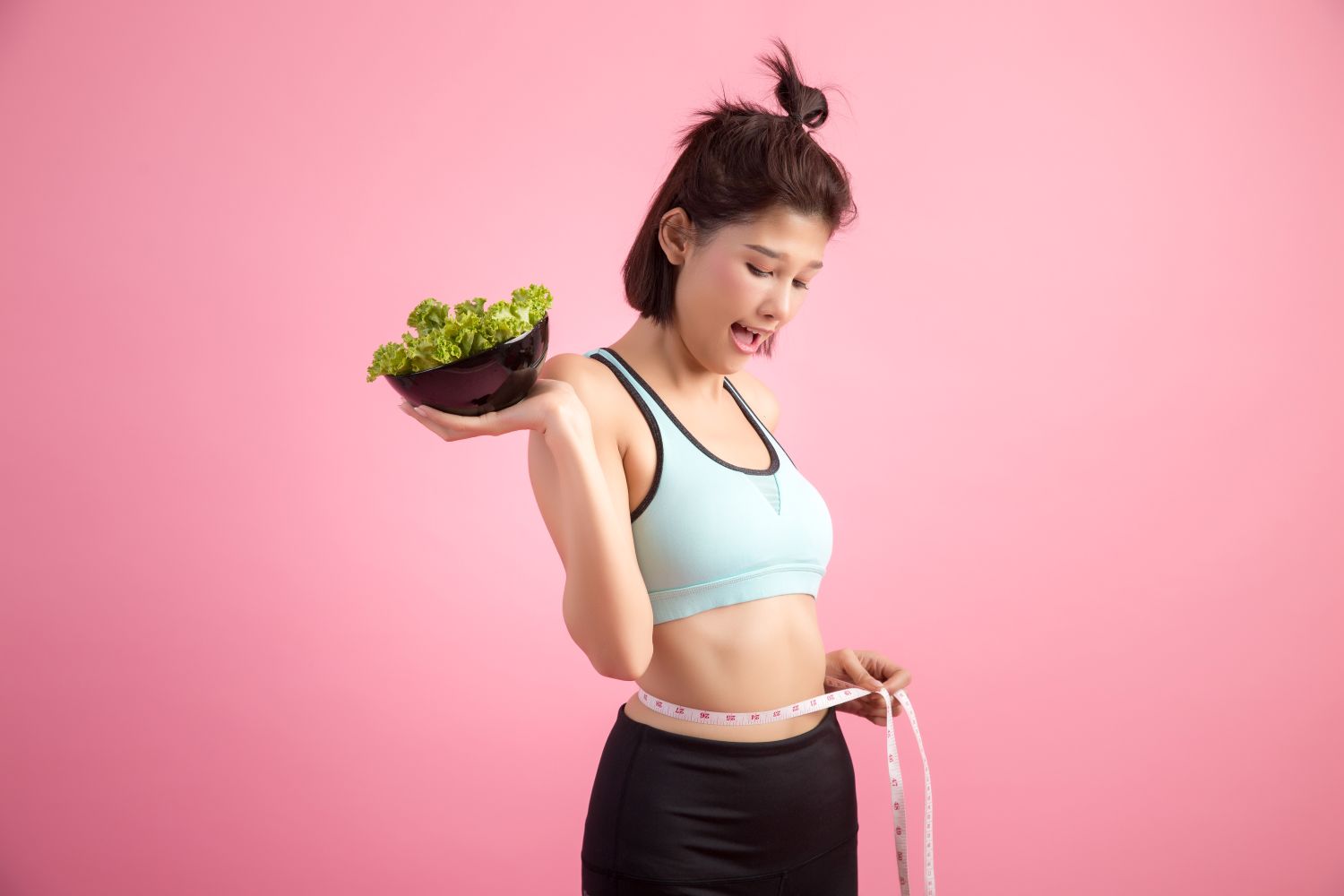 girl measuring waist holding a salad